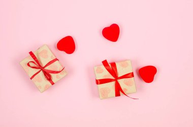 Kırmızı kalpler ve hediye kutuları el işi kağıdına ve pembe arka plana kırmızı kurdele bağlamış. Sevgililer Günü konsepti, düğünler, nişanlar, Anneler Günü, doğum günü. Metin için yeri olan tebrik kartı 