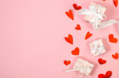 Gift box and red paper hearts on pink background. Concept of Valentine day. Greeting card for Valentine,  Mother day or birthday.