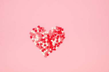 Many various sugar red, pink and white hearts laid out in the shape of a heart on pink background. Concept of Valentine day. Greeting card for Valentine,  Mother day or birthday.