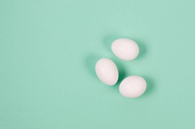Fresh white chicken eggs close-up onblue background. Group of three eggs.