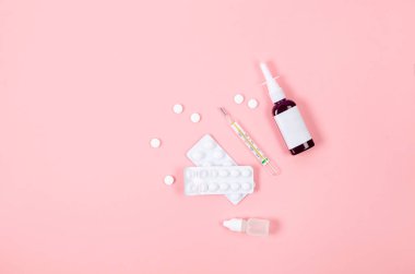 Medicines for treatment- pills, spray bottles, blister and thermometer on pink background, Pharmaceuticals and medicine. Illness concept. 