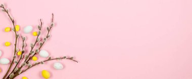 Paskalya renkli çikolata yumurtaları ve pastel pembe arka planda brunch söğüdü. Paskalya tatili ve gelenek kavramı. Tatil için hazırlık. 
