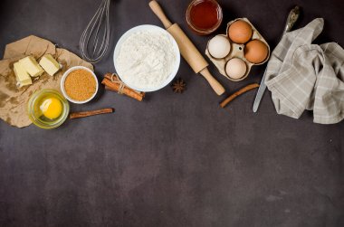 Koyu mutfak atölyesinde un, yumurta, şeker ve tarçın içeren ev yapımı kurabiyeler pişirmek. Mutfak arka planı, kopyalama alanı, genel görünüm