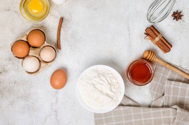 Baking homemade cookies on gray kitchen worktop with ingredients -flour, eggs,  sugar and  cinnamon. culinary background, copy space, overhead view