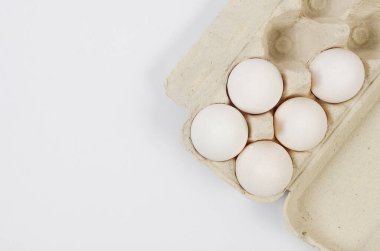 Fresh white chicken eggs in a cardboard tray close-up on white background. Group of five eggs.