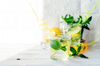 Bardakta mojito kokteyli, beyaz ahşap masada nane ve limon yaprakları kokteyl yaz içecekleri konsepti.