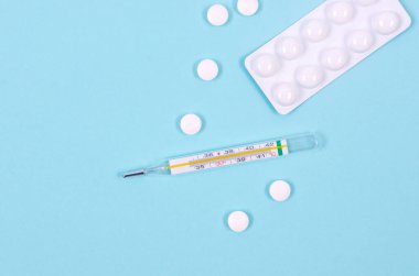 Medicines for treatment- pills, spray bottles, blister and thermometer on a blue background, Pharmaceuticals and medicine. Illness concept. 