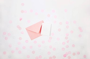 İçinde boş kart ve beyaz arka planda renkli kağıt konfetisi olan pembe bir zarf. Tebrik kartı ve parti davetiye şablonu tasarımı. Anneler günü veya doğum günü için.