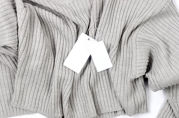 白色空白纸板标签 灰色毛衣上有绳子 在衣服上贴上空白的标签 以放置你的设计 价格标签 地址标签 购物概念 — 图库照片