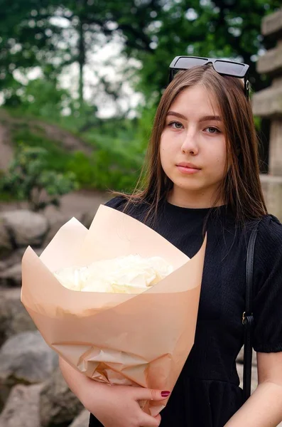 Fiatal Lány Fekete Ruhában Egy Gyönyörű Csokor Fehér Rózsa Csomagolva — Stock Fotó