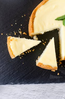 Klasik vanilyalı Cheesecake New York tabağı, Yakından Bakış. Siyah taş tahtada beyaz zemin üzerinde nane yaprağı olan nefis peynirli kek.. 