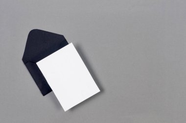 Gri arkaplandaki mesaj için boş beyaz kartı olan siyah bir zarf. Boş davet veya kopyalama alanı olan tebrik kartı modeliName