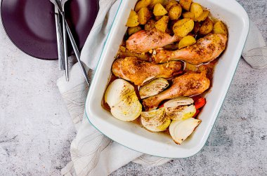 Kızarmış tavuk bacağı, patates, soğan ve havuç tablada salata ve masada lezzetli bir öğle yemeği..