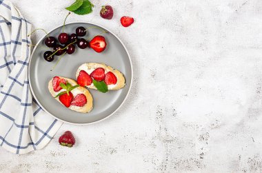 Açık sandviçler, krem peynirli zanaatkar ekmek, taze çilek ve çimento kaplı taze naneli bitki. Atıştırmalık, sağlıklı kahvaltı., 