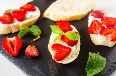 Açık sandviçler, krem peynirli zanaatkar ekmek, taze çilek ve çimento kaplı taze naneli bitki. Atıştırmalık, sağlıklı kahvaltı., 