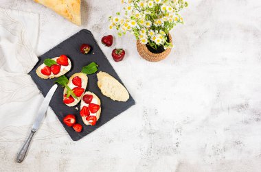 Açık sandviçler, krem peynirli zanaatkar ekmek, taze çilek ve çimento kaplı taze naneli bitki. Atıştırmalık, sağlıklı kahvaltı., 