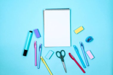 Okul defteri ve mavi arka planda çeşitli kırtasiye malzemeleri. Okulda okumak için malzemeler. Flatlay, maket yap. Renkli kırtasiye iskeleti. Okul konseptine dönelim.. 