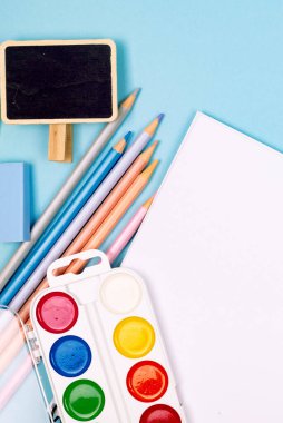 Okul defteri ve mavi arka planda çeşitli kırtasiye malzemeleri. Okulda okumak için malzemeler. Flatlay, maket yap. Renkli kırtasiye iskeleti. Okul konseptine dönelim.. 