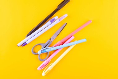 Sarı arka planda okul için çeşitli kırtasiyeler. Okula ve eğitim konseptine dönüş, okulda okumak için malzemeler. 