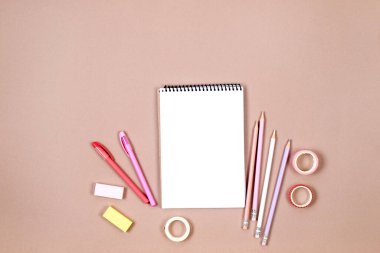 Okul defteri ve bej arka planda pembe renkli kızlar için çeşitli kırtasiye malzemeleri. Okulda okumak için malzemeler. Flatlay, maket yap. Renkli kırtasiye iskeleti. Okul konseptine dönelim.. 