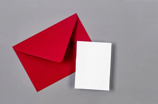 Ped envelope with empty white card for text on grey background. Blank invitation or greeting card mockup with copy space