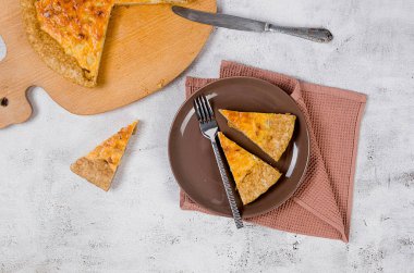 Tavuklu kiş turtası, şampiyon mantarlar, beyaz masada soğan ve peynir. Ev yapımı turta, parçalara bölünmüş. Fransız mutfağı.