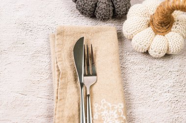 Boş bir tabak ve çatal bıçak setiyle sonbahar arkaplanı ve gri beton arka planda dekoratif balkabağı. Şükran Günü yemeği konsepti, mesaj için boş yer.. 