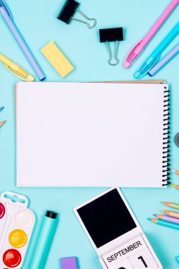 Okul defteri ve mavi arka planda çeşitli kırtasiye malzemeleri. Okulda okumak için malzemeler. Flatlay, maket yap. Renkli kırtasiye iskeleti. Okul konseptine dönelim.. 
