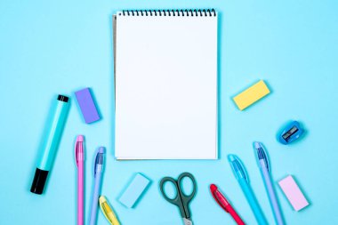Okul defteri ve mavi arka planda çeşitli kırtasiye malzemeleri. Okulda okumak için malzemeler. Flatlay, maket yap. Renkli kırtasiye iskeleti. Okul konseptine dönelim.. 