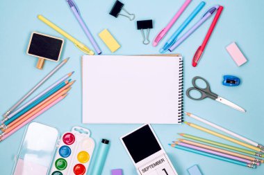 Okul defteri ve mavi arka planda çeşitli kırtasiye malzemeleri. Okulda okumak için malzemeler. Flatlay, maket yap. Renkli kırtasiye iskeleti. Okul konseptine dönelim.. 