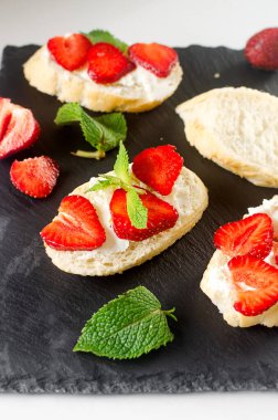 Açık sandviçler, krem peynirli zanaatkar ekmek, taze çilek ve çimento kaplı taze naneli bitki. Atıştırmalık, sağlıklı kahvaltı., 