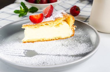 Bir dilim Karpatka turtası. Geleneksel Polonya pastası Karpatka gri beton arka planda. Kremalı pasta 'Karpatya dağı' kremalı, pudra şekerli ve çilekli..