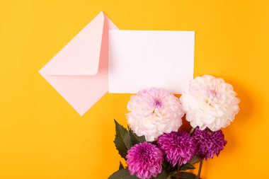 Sarı arka planda pembe zarf, beyaz ve mor yıldız çiçekleri olan boş tebrik kartı modeli. Boş davet veya kopyalama alanı olan tebrik kartı modeliName