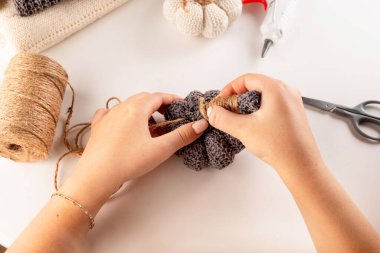 Genç kız eski kazaklardan gamzeli balkabağı yapıyor, konsepti yeniden kullan. Eski giysiler, hobiler, diy. Şükran Günü ve sonbahar tatili için el işleri.. 