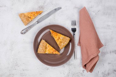 Tavuklu kiş turtası, şampiyon mantarlar, beyaz masada soğan ve peynir. Ev yapımı turta, parçalara bölünmüş. Fransız mutfağı.