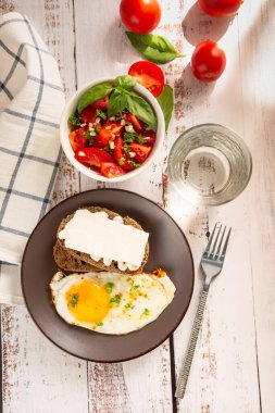 Fırında yumurta, domatesli salata ve peynirli sandviç. Kahvaltı için eski beyaz ahşap masada..