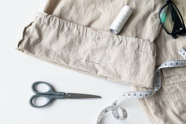 linen trousers with tools to repair old clothes. Sewing and home needlework. Circular fashion, fast fashion, Sustainable, zero waste lifestyle concept