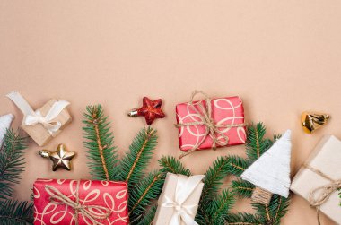 El işi kağıdına sarılı hediye kutuları kurdele, çam brunch 'ı ve bej arka planda takılar. Xmas kutlaması, Noel geçmişi. Greetig kartı.