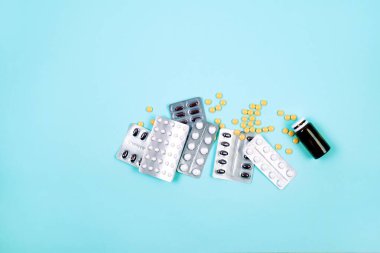 Bir sürü farklı hap ve kapsül, mavi arka planda şişeler. Sağlık, tıp konsepti.