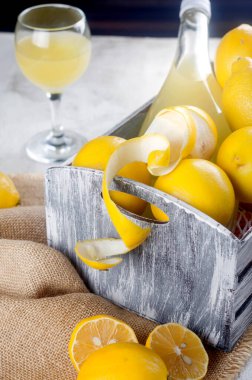 Cam şişede limoncello ve gri arka planda taze olgun sarı limonlar, geleneksel ev yapımı tatlı İtalyan limon likörü, güçlü alkollü içecek ve taze olgun limonlar..