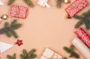 El işi kağıdına sarılı hediye kutuları kurdele, çam brunch 'ı ve bej arka planda takılar. Xmas kutlaması, Noel geçmişi. Greetig kartı.