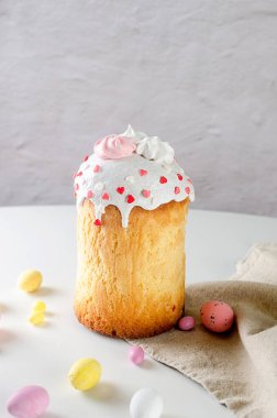 Paskalya yemeği için beyaz masaya yerleştirilmiş paskalya pastası, renkli süslemeli çikolata yumurtaları, söğüt ağacı ve tatil süslemeleri. Bahar tatili konsepti. Mutlu Paskalyalar