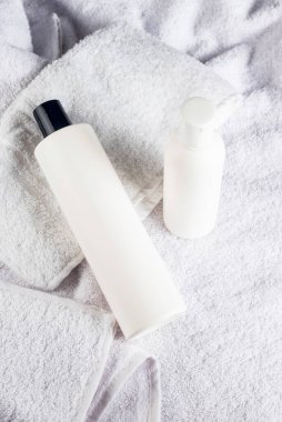 Ahşap masa üzerinde havlu bulunan şampuan şişelerinin beyaz kozmetik maketi. Saç bakımı kavramı. 