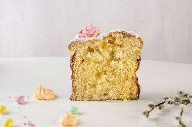 Paskalya yemeği için beyaz masaya yerleştirilmiş paskalya pastası, renkli süslemeli çikolata yumurtaları, söğüt ağacı ve tatil süslemeleri. Bahar tatili konsepti. Mutlu Paskalyalar