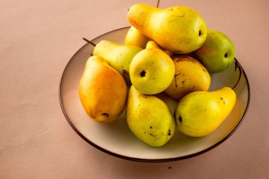 Bej kaplamalı sarı-yeşil armutlar. Parlak sulu meyveler.