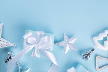 Noel mavisi arka plan. Mavi kağıda sarılı tatil hediyesi kutusu, toplar, mavi arka planda parıltı, neşeli mesajınız için yer var.. 