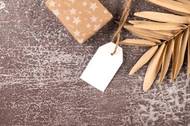 Hediyelerle dolu boş beyaz etiket ve karanlık arka planda Noel süsü. Noel tebrik kartı maketi.