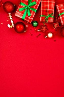 Kırmızı arkaplanda yeşil kurdeleli kırmızı kağıtlara sarılı Noel hediyeleriyle dolu Noel arkaplanı. Tebrik kartı, maket.