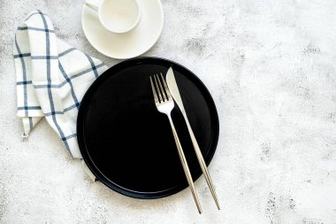Siyah tabak, çatal bıçak takımı ve beyaz bardaklı minimalist masa. Yemek fotoğrafçılığı ve restoran pazarlaması için mükemmel., 