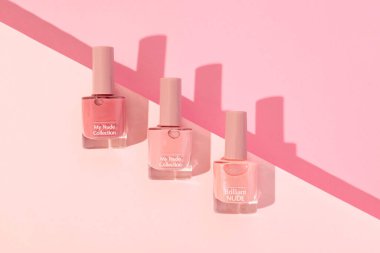 Pembe arka planda üç şişe çıplak tırnak cilası. Güzellik ve moda için mükemmel., 